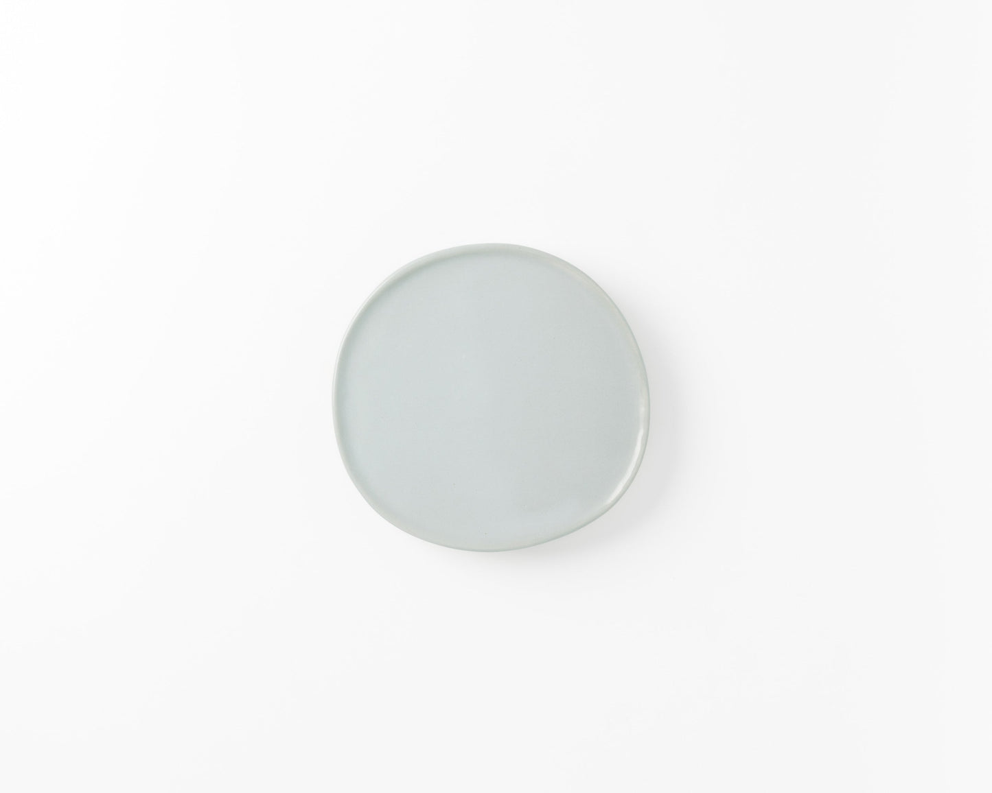 Minimalist round ceramic plate in light blue on a white background