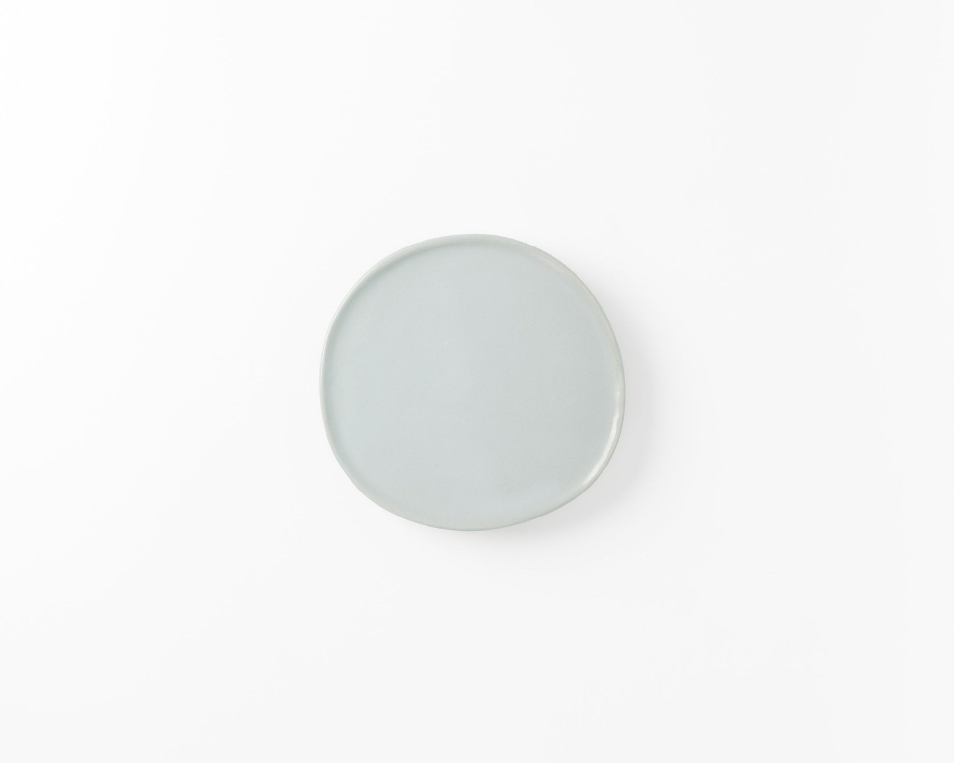 Minimalist round ceramic plate in light blue on a white background