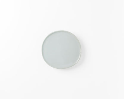 Minimalist round ceramic plate in light blue on a white background