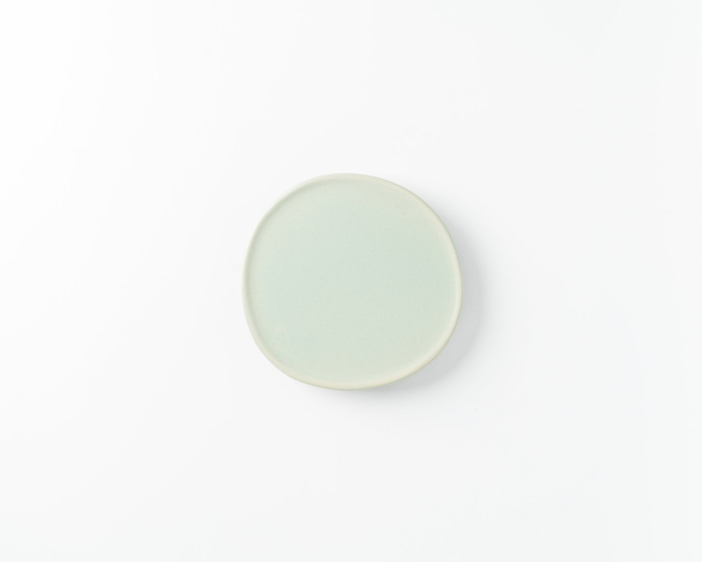 Minimalist light green ceramic side plate on white background