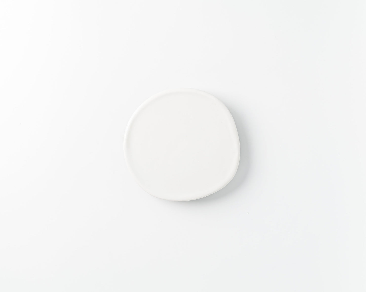 Minimalist handmade irregular white ceramic plate on a white background