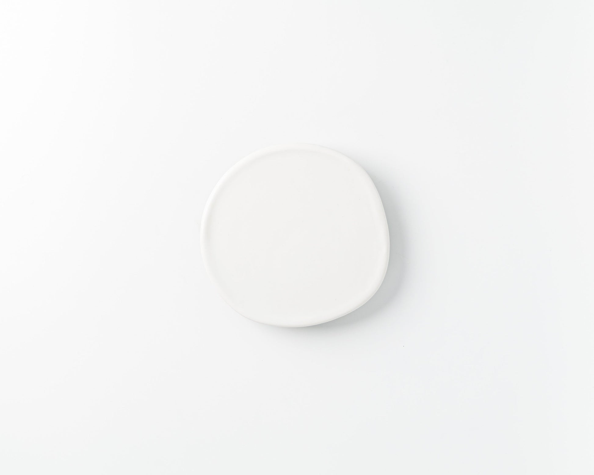 Minimalist handmade irregular white ceramic plate on a white background
