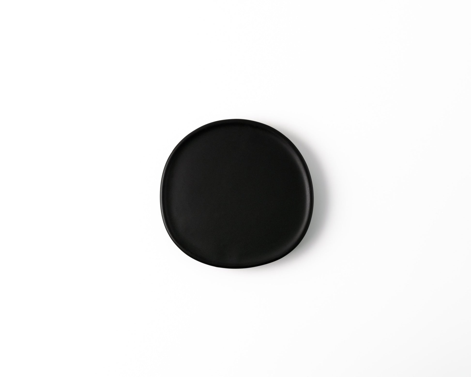 Round black ceramic plate with smooth edges on white background