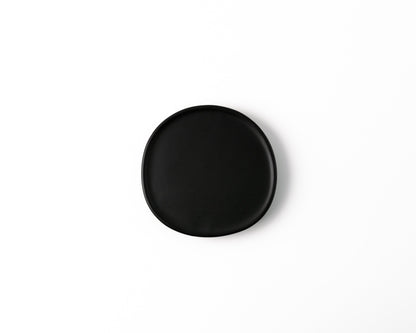Round black ceramic plate with smooth edges on white background