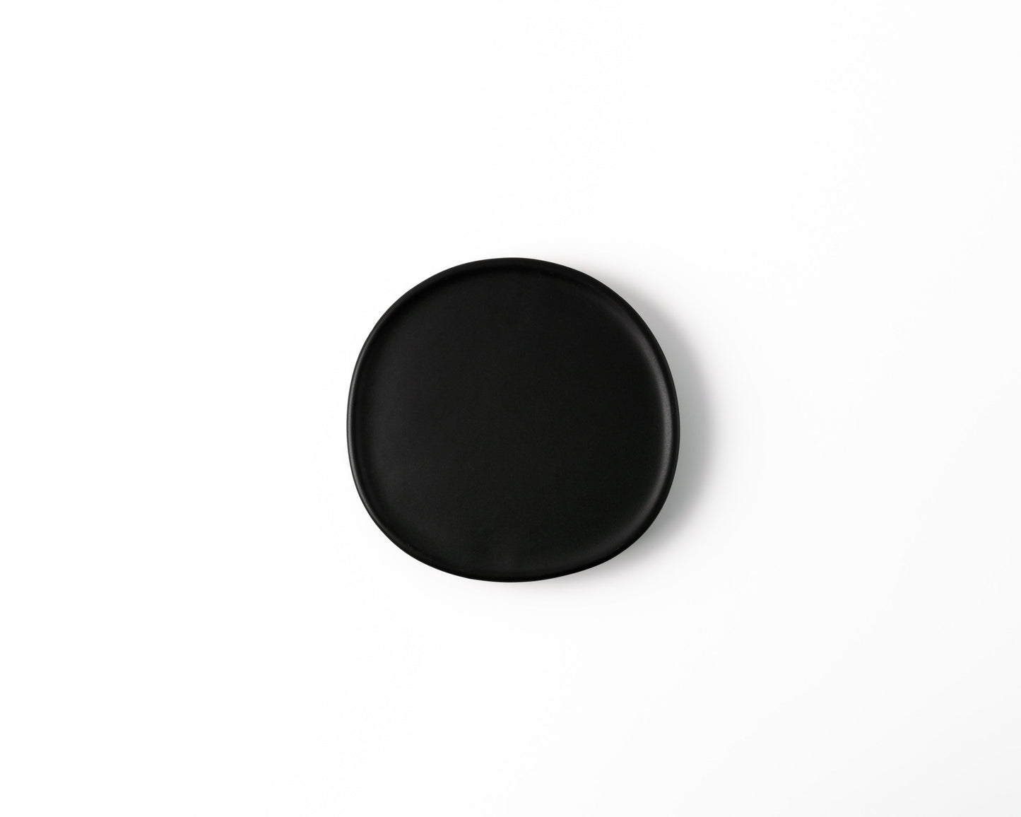 Round black ceramic plate with matte finish on white background