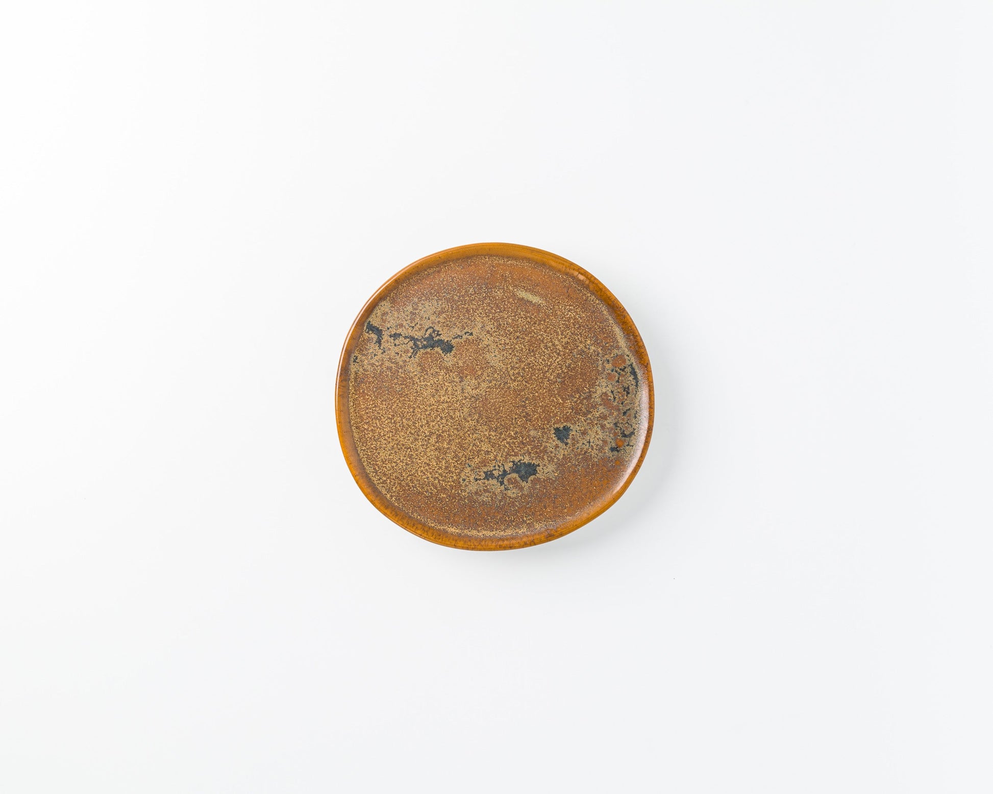 Round ceramic plate with brown speckled glaze and black textured patterns on white background