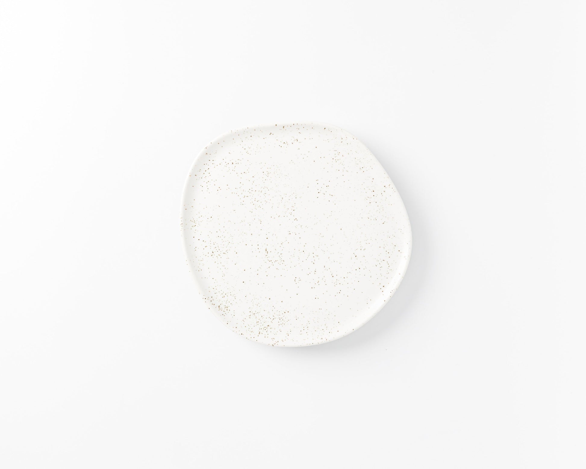 White ceramic plate with irregular shape and speckled gold dots on a white background