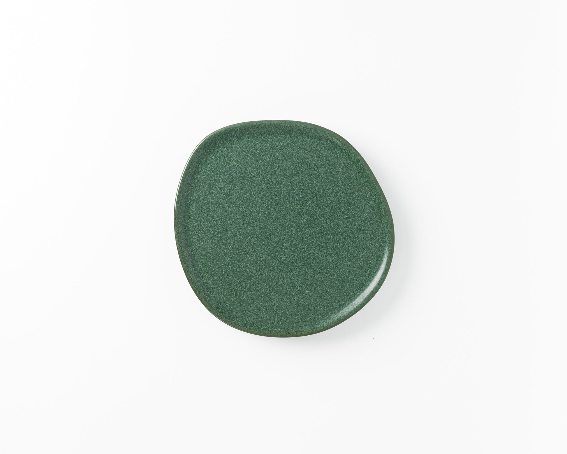 Green ceramic plate with irregular rounded shape on white background