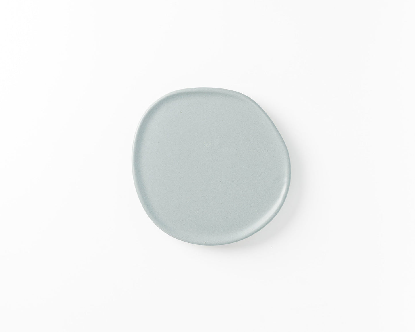 Minimalist round light gray ceramic plate with an irregular edge on white background