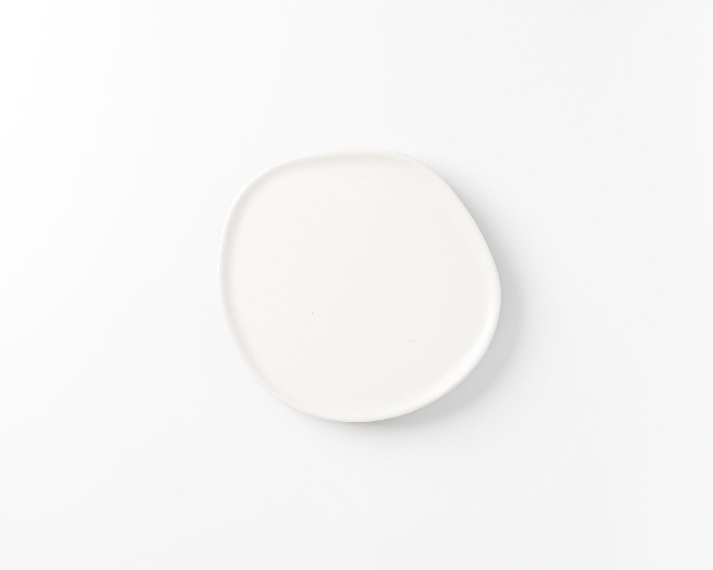 White ceramic plate with organic, irregular round shape on white background