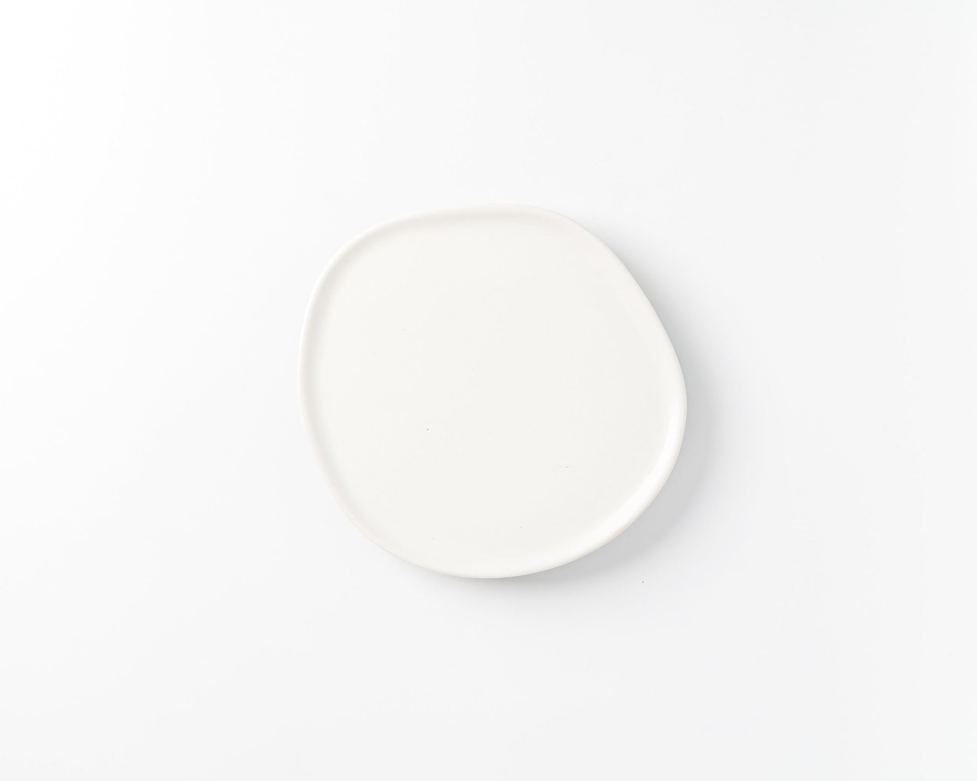 White ceramic plate with organic, irregular round shape on white background
