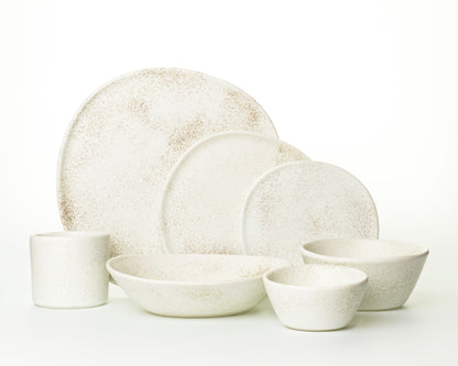 White ceramic dinnerware set with speckled brown pattern, includes plates, bowls, and mug
