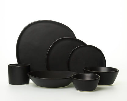 Matte black ceramic dinnerware set with plates, bowls, and cup on white background