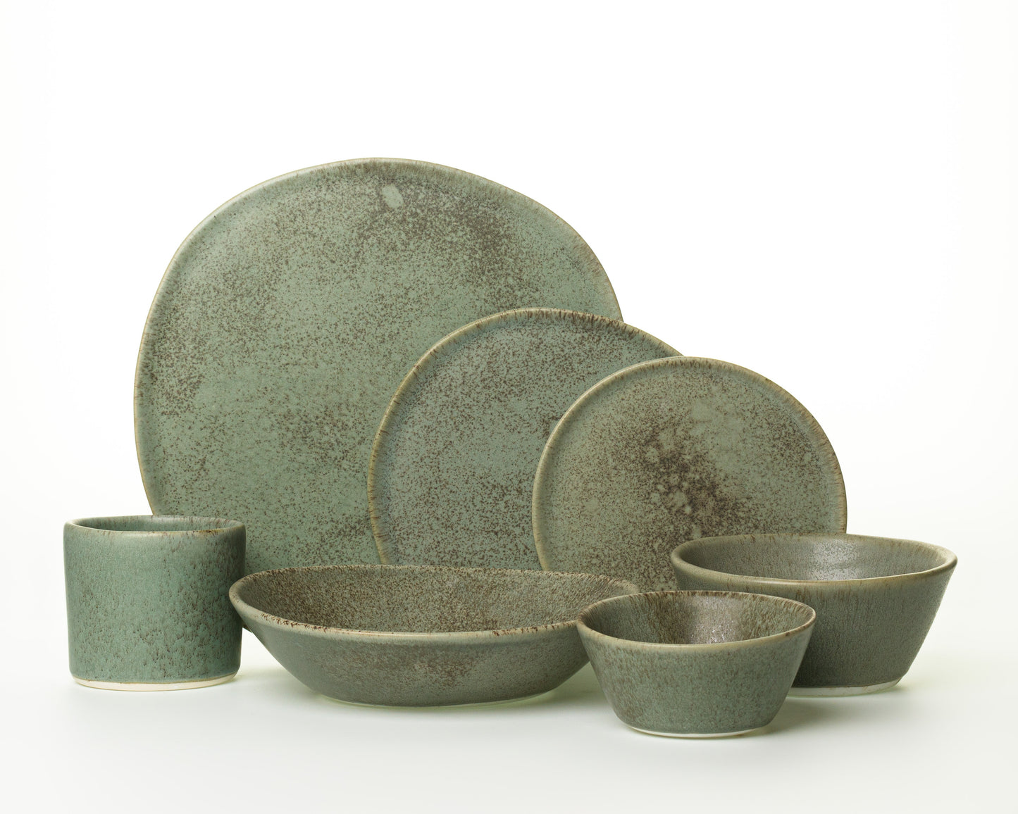 Speckled green ceramic dinnerware set with plates, bowls, and a cup on white background