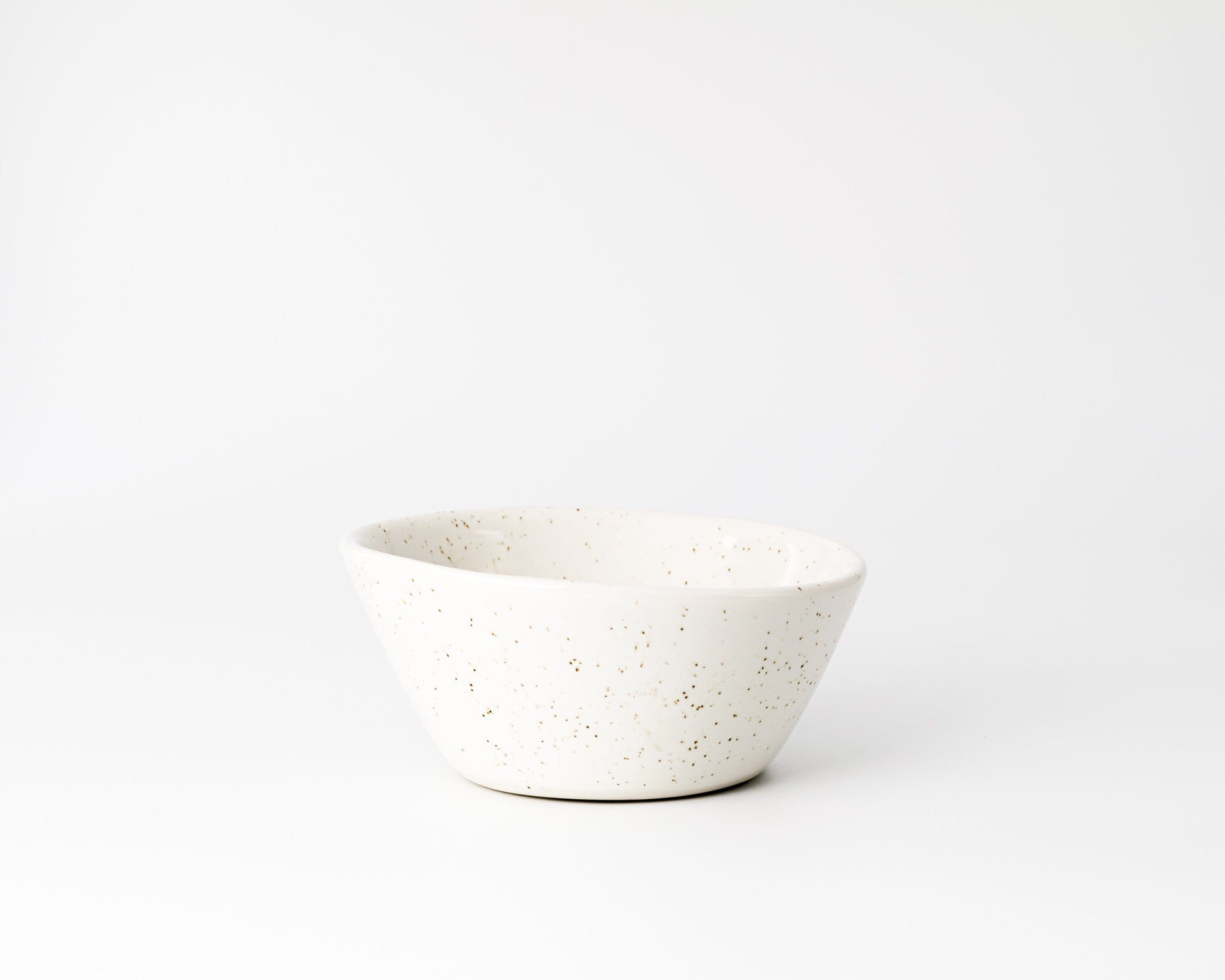 White ceramic bowl with brown speckled pattern on a white background