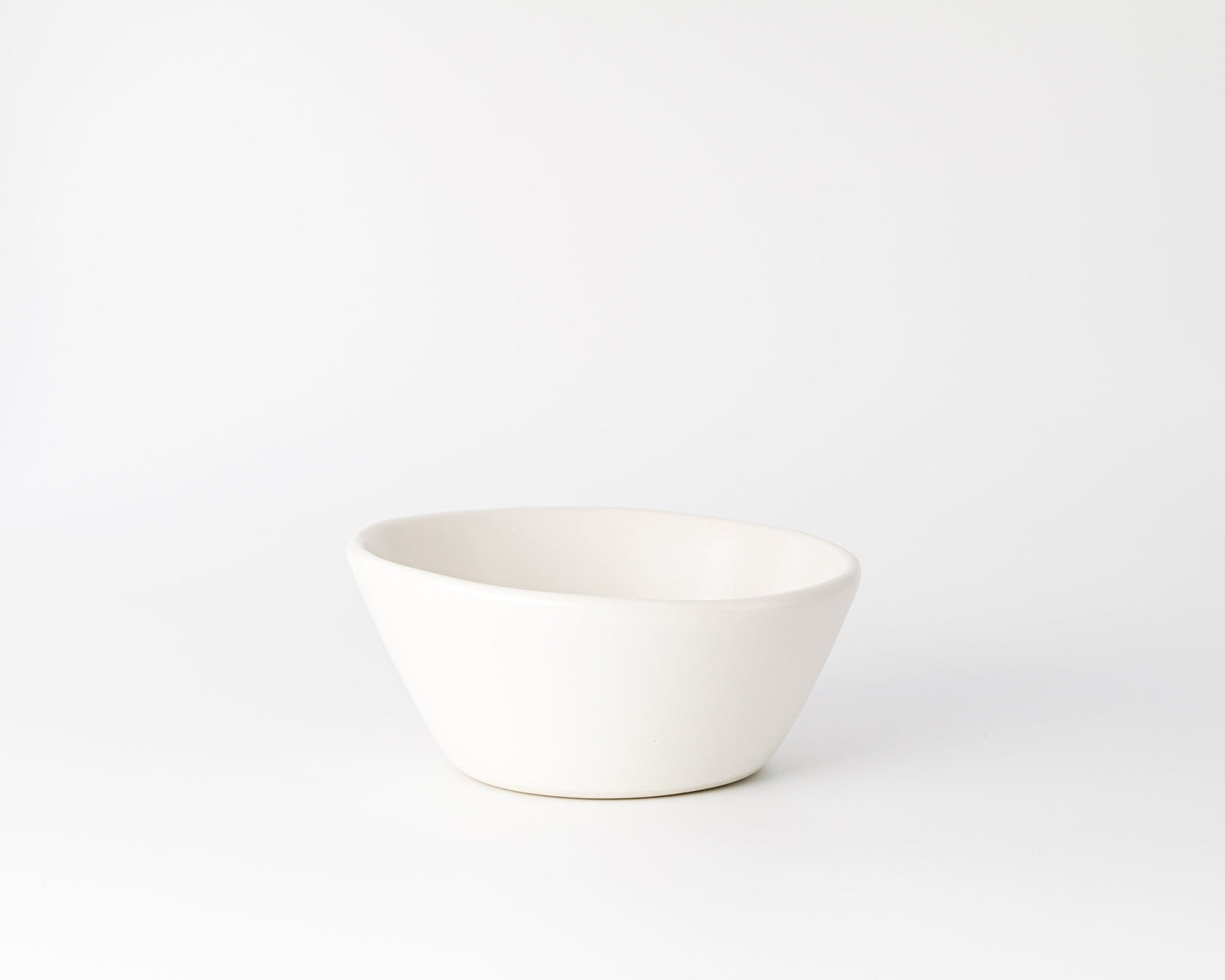 White ceramic bowl with an organic, irregular round shape on white background