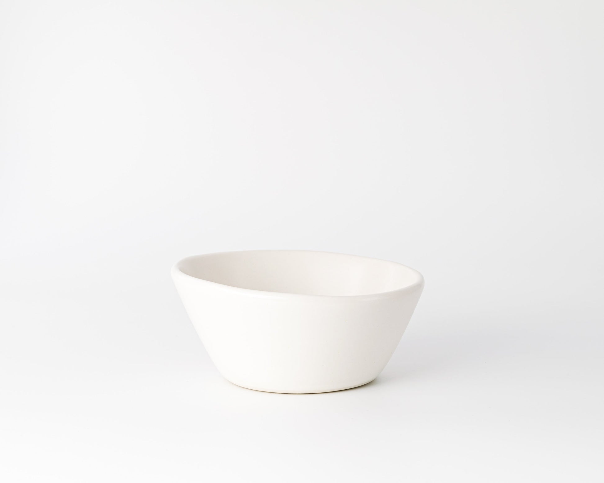 White ceramic bowl with an organic, irregular round shape on white background