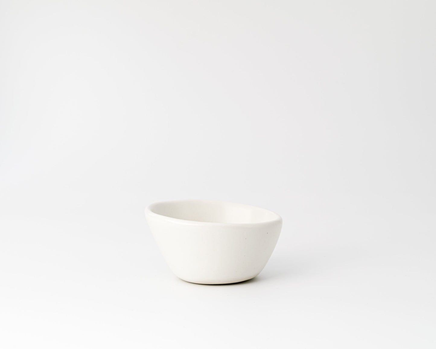 Minimalist white ceramic bowl with smooth curved design on white background