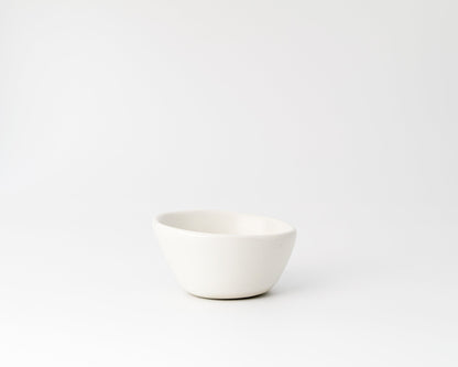 Minimalist white ceramic bowl with smooth curved design on white background