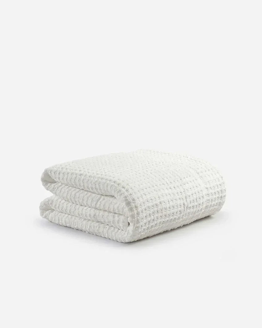 Folded off-white waffle texture comforter on a plain white background