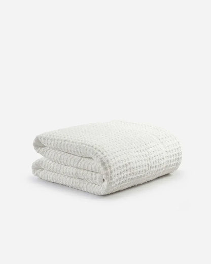 Folded off-white waffle texture comforter on a plain white background