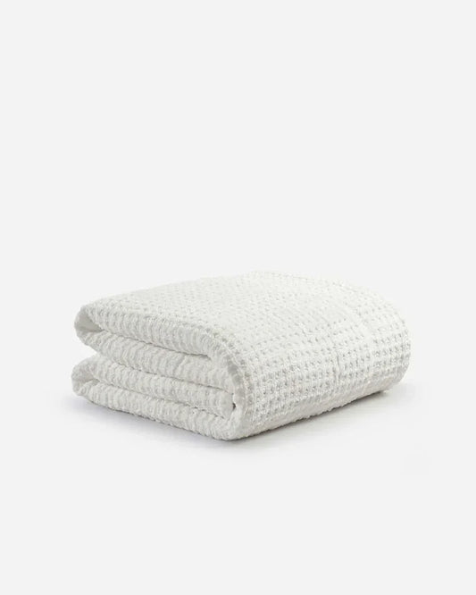 Folded off-white waffle texture comforter on a plain white background