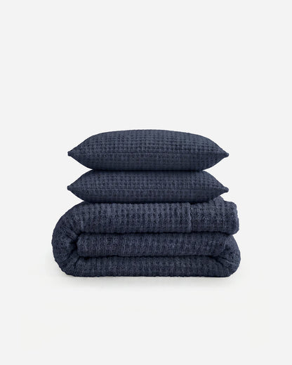 Snug Waffle Comforter Bundle in Midnight with two matching shams folded and stacked on white background