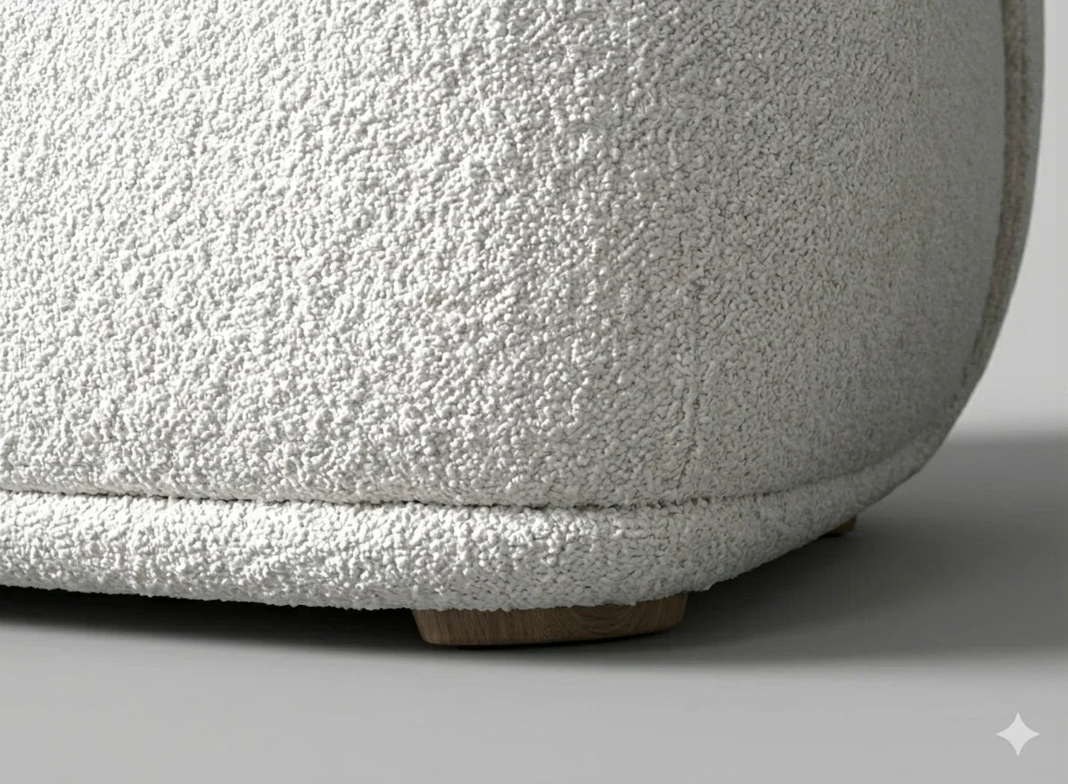 Close-up view of the solid wood base and precision stitching on a white boucle barrel chair showcasing high-quality construction and textured upholstery detail.