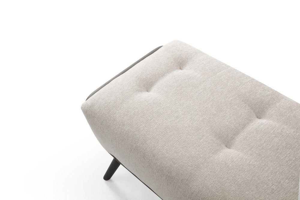 Overhead close-up of beige button tufted fabric bench seat with dark gray vegan leather trim and black steel leg