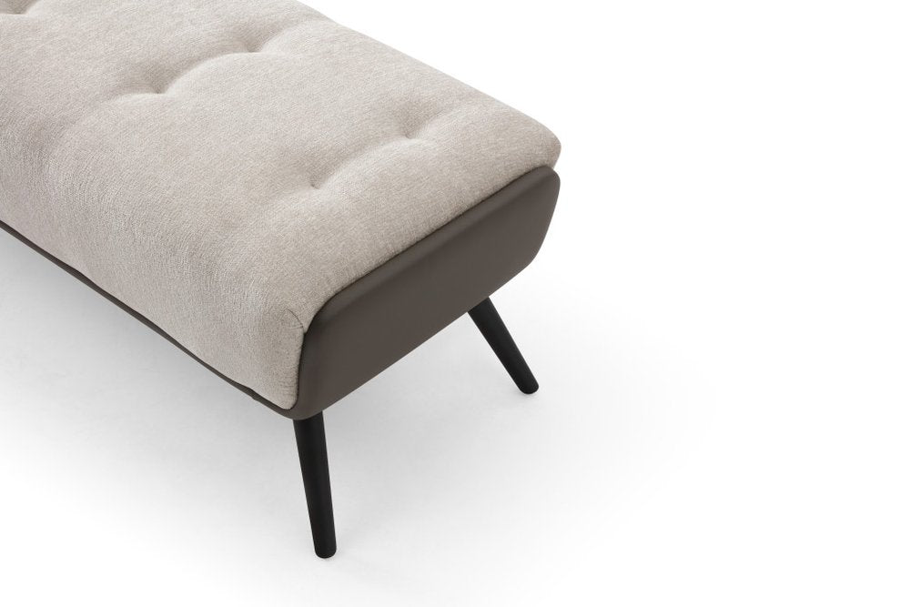 Angled close-up of beige tufted fabric bench end with dark gray vegan leather side panel and black splayed steel legs on white background