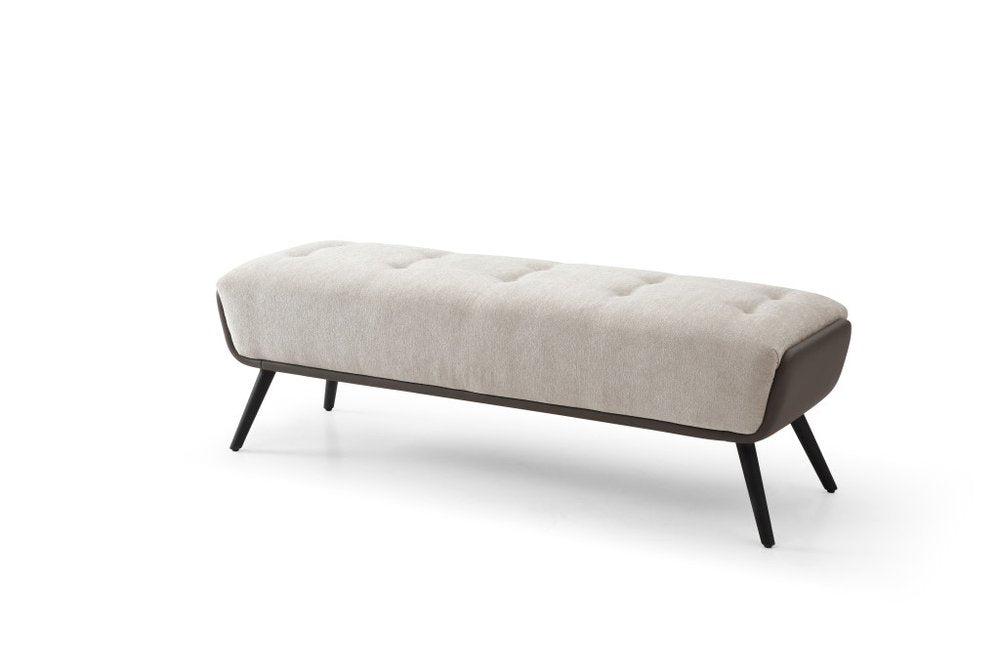 Beige button tufted vegan leather bench with dark gray side panels and black splayed steel legs shown at an angle on white background