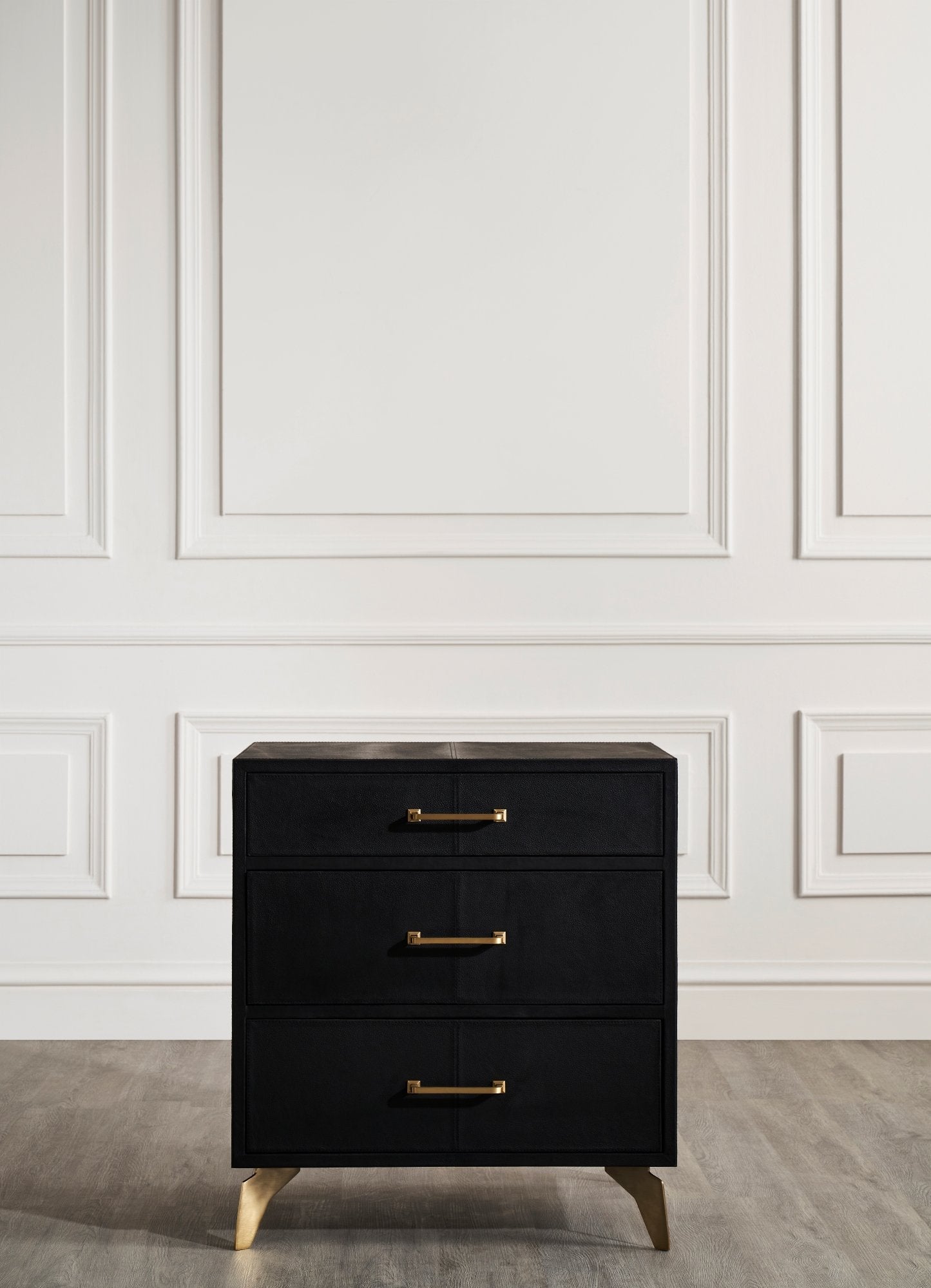 Berkeley Leather Nightstand black three drawer full view brass legs white paneled wall 