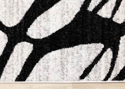 Black and gray abstract area rug low-angle edge view showing dense polypropylene pile depth and bold linear pattern contrast