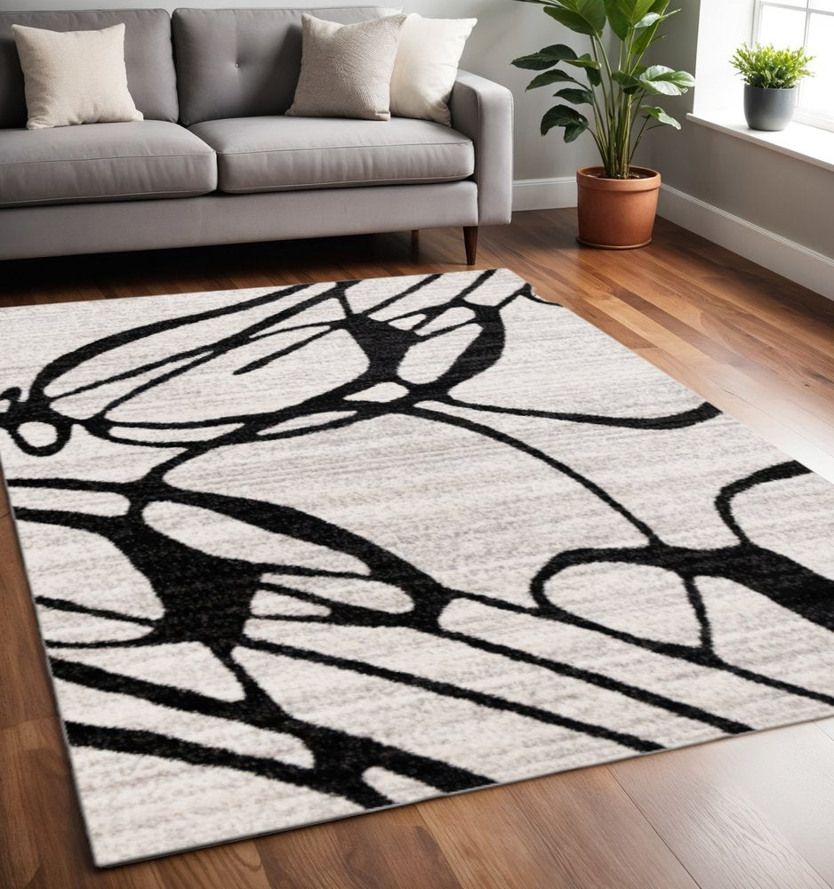 Black and gray abstract area rug styled in a bright living room with gray sofa hardwood floors and indoor potted plants