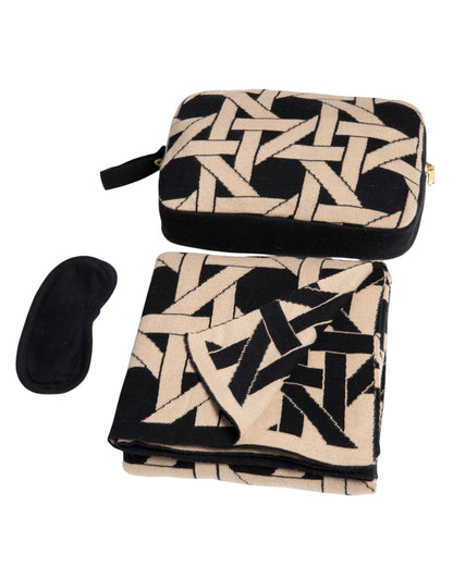 Black organic cotton travel blanket set with geometric pattern including folded blanket eye mask and compact pouch with gold zipper