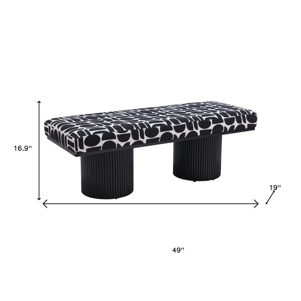 Dimension diagram of black and white geometric upholstered bench showing 49 inches wide 16.9 inches high and 19 inches deep with dual ribbed black cylindrical pedestal legs