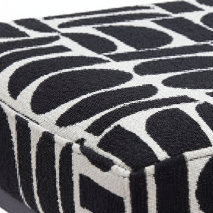 Angled close-up of black and white geometric polyester fabric bench seat corner showing texture and pattern detail with black pedestal leg base