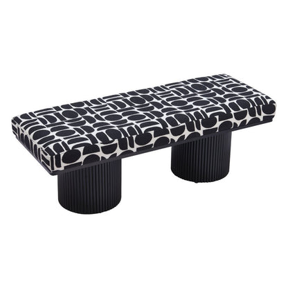 Overhead angled view of black and white geometric upholstered bench seat with dual ribbed black cylindrical pedestal legs on white background