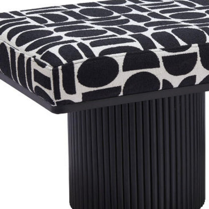 Close-up of black and white geometric patterned bench seat with ribbed black cylindrical pedestal leg detail on white background