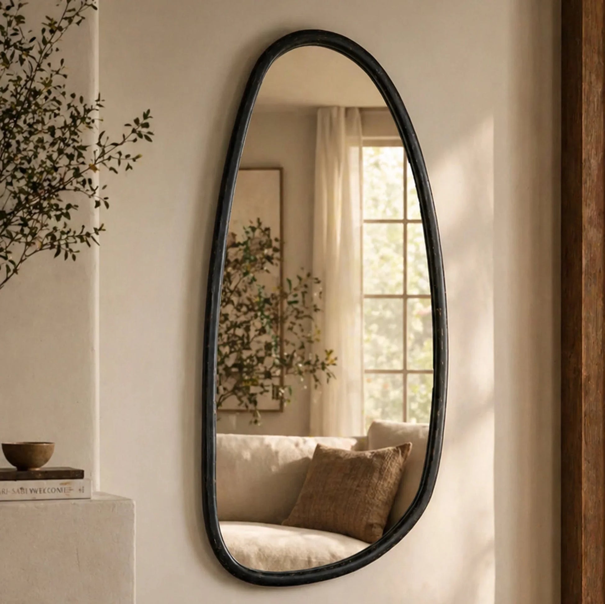 Blackwash mango wood wall mirror styled in a warm living room reflecting natural light with organic black frame and neutral decor

