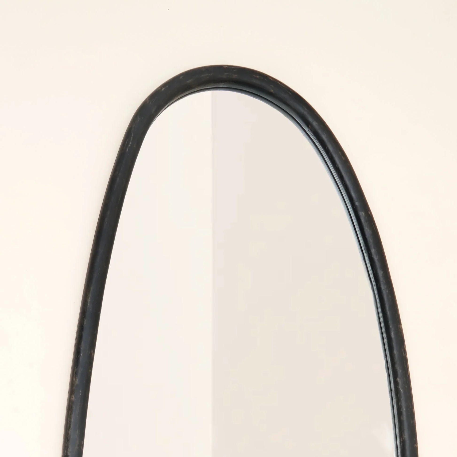 Close-up of blackwash mango wood wall mirror top arch showing handcrafted frame detail and smooth curved silhouette against neutral wall

