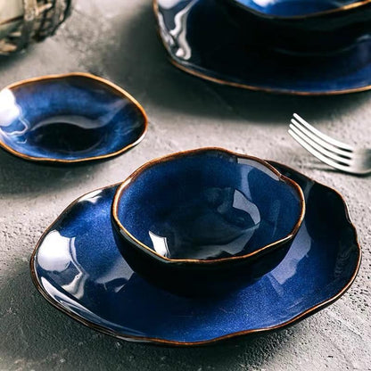 An elegant place setting from the Blue European Porcelain Dinnerware Set, featuring premium hand-painted tableware with egg shaped porcelain plates and dark blue glazed bowls on a stone tabletop.