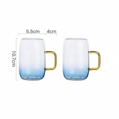 Two blue gradient glass cups with gold handles showing dimensions 5.5cm width and 10.7cm height on white background