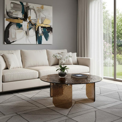 Bronze tempered glass round coffee table in a modern living room with ivory sofa, white orchid centerpiece, geometric area rug, and bold abstract art above