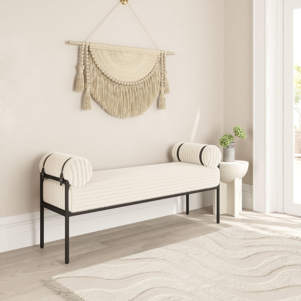 Cream corduroy upholstered bedroom bench styled in neutral living room with macrame wall hanging area rug and side table