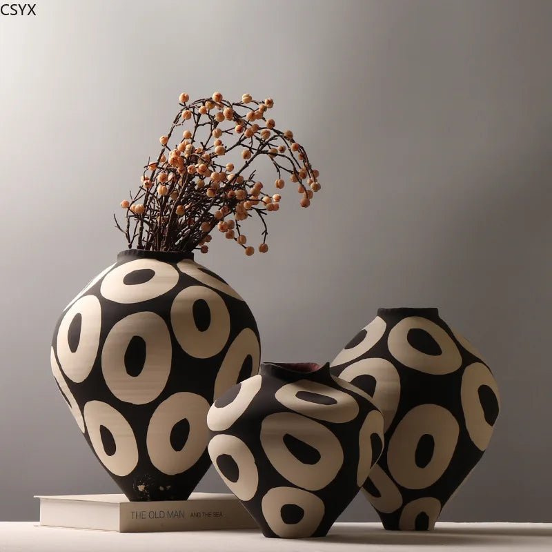 Three Aurelia geometric decorative vases with light circular patterns on dark rounded bodies, with berry-like branches arranged in the tallest vase.