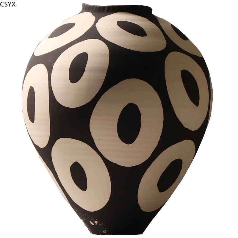 Front view of an Aurelia geometric decorative vase with light circular patterns on a dark rounded body, a narrow opening, and a tapered base against a white background.