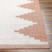 Close-up of Hauteloom Djugun Peach Fuzz indoor/outdoor rug with Aztec geometric pattern in peach and white on wood floor.