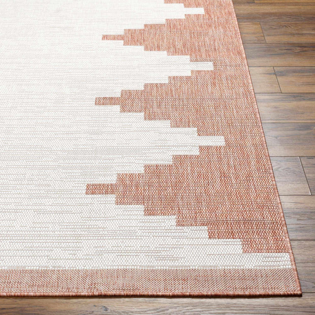 Close-up of Hauteloom Djugun Peach Fuzz indoor/outdoor rug with Aztec geometric pattern in peach and white on wood floor.