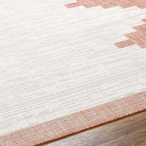 Close-up of Hauteloom Djugun Peach Fuzz rug, showing Aztec pattern & durable polypropylene border on wood floor.